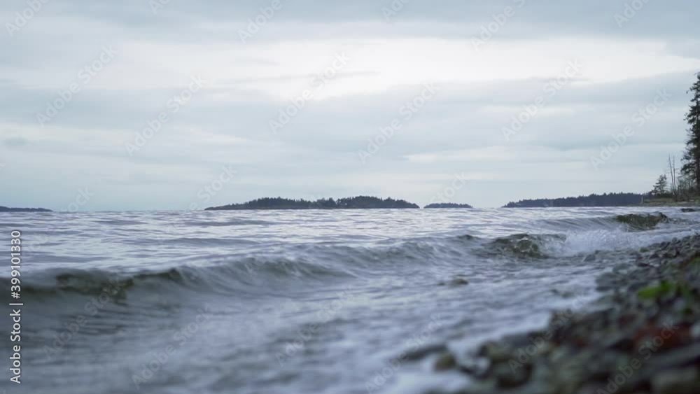 Waves rolling at a stone beach on a cloudy summer day in Tofino (Canada.) Steady slowmotion shot Waves rolling at a stone beach on a cloudy summer day in Tofino (Canada.) Steady slowmotion shot