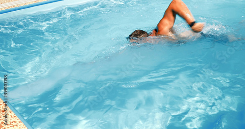 A young man trains in a home pool. Athlete swims in countercurrent. Fitness training as a healthy lifestyle.