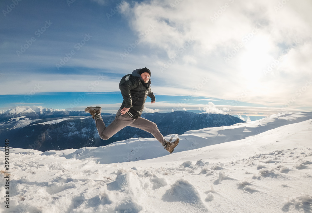 Traveler man jumps to the top of the mountain with snow. Victory of the'mountaineer.