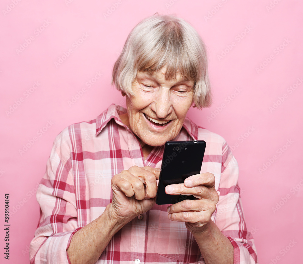 Portrait of old smiling grey-haired lady looking at screen of mobile phone Portrait of old smiling grey-haired lady looking at screen of mobile phone