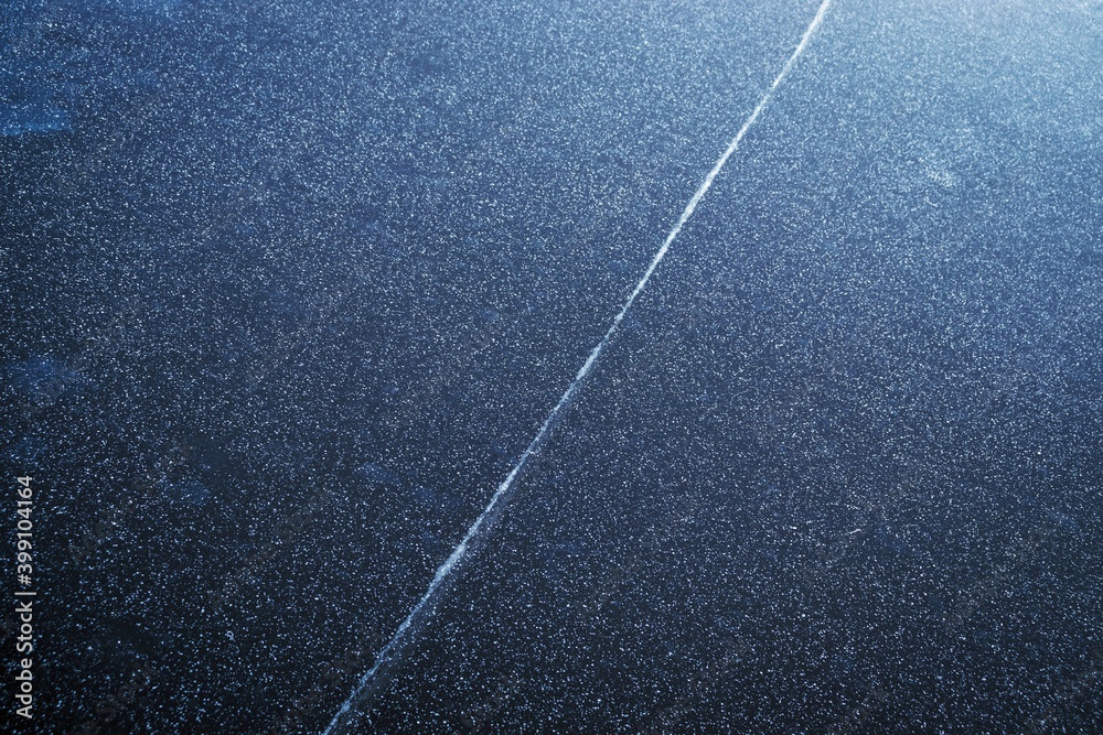Fototapeta premium Abstract texture of dark ice with snow crystals and white line on the surface. Frozen river