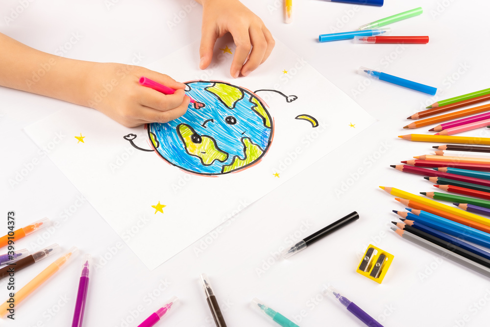 Child girl draws planet earth with multicolored felt-tip pens on a white sheet. Child girl draws planet earth with multicolored felt-tip pens on a white sheet.