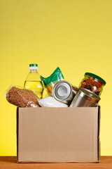 Food Donation concept. Donation Box With food For Donation On Yellow Backround. Vertical shot.