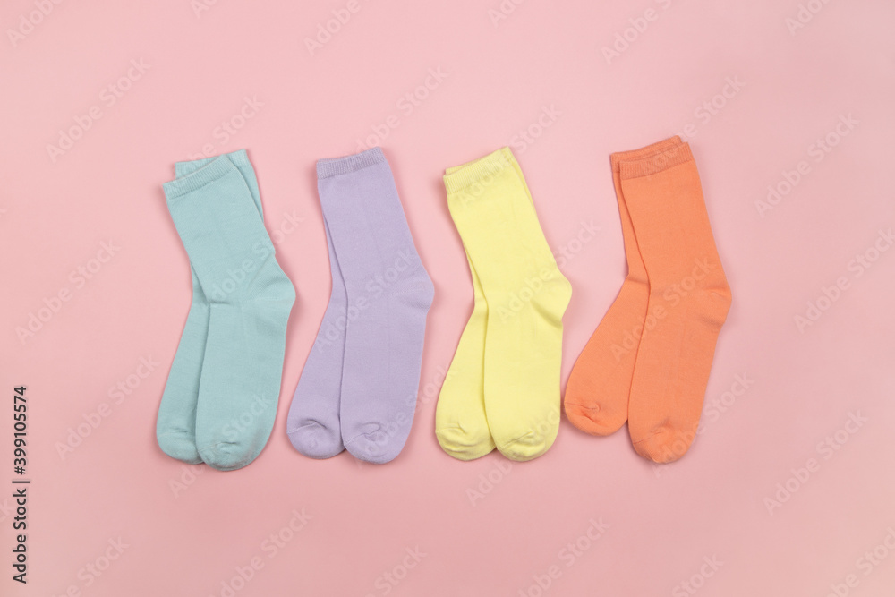 Colored children's socks without a pattern, pink, lilac, yellow, orange on a pink background with a place for text, copy space, flatly, minimal style. Concept for children's clothing, housekeeping Colored children's socks without a pattern, pink, lilac, yellow, orange on a pink background with a place for text, copy space, flatly, minimal style. Concept for children's clothing, housekeeping
