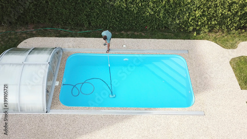Cleaning the home pool. The man sucks and cleans the swimming pool. Seasonal work from an aerial perspective.