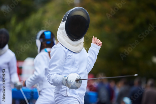 Athletes fencing in a suit uniform with a sword and mask, competition or warm-up. An active Olympic sport.