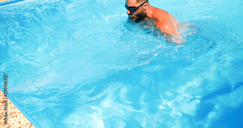 Obraz na płótnie A young man trains in a home pool. Athlete swims in countercurrent. Fitness training as a healthy lifestyle. w salonie