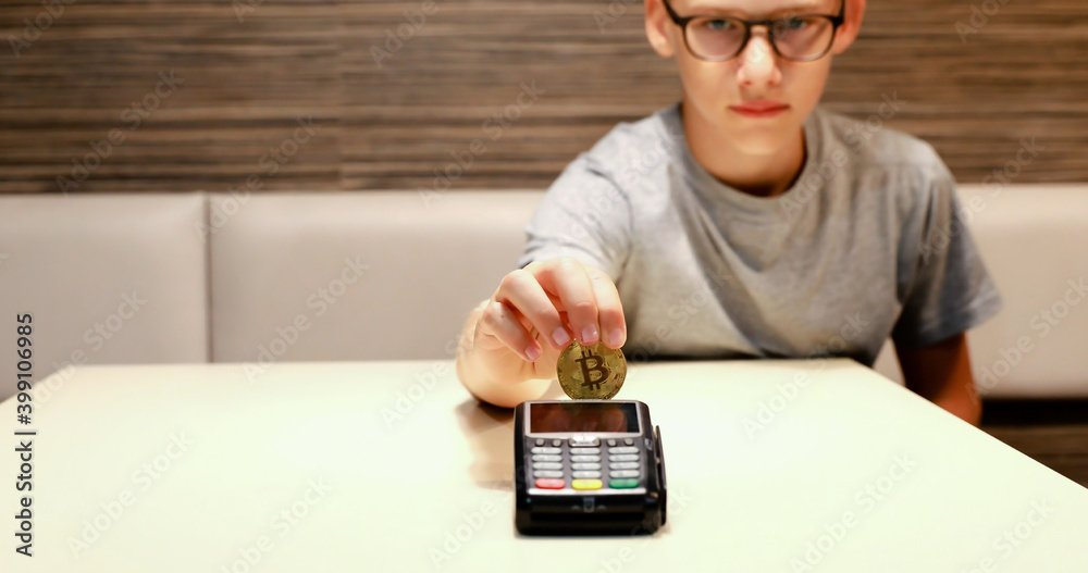 A young boy makes a payment with cryptocurrencies. Use of digital currency for payment. Illustrative bitcoin payment.