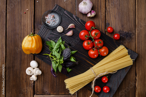 Fresh vegetables and spaghetti, wooden background