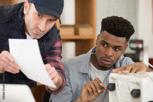 Fotografie workmen follow instructions for the assembly of an electrical appliance