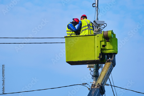 Male workers repairing a security camera tower while standing at a high altitude