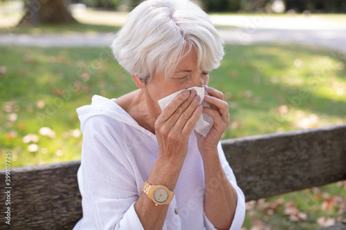 senior woman has a runny nose having flowers pollen allergy
