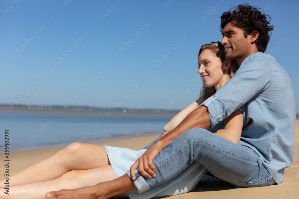 pretty young couple sitting on the beach