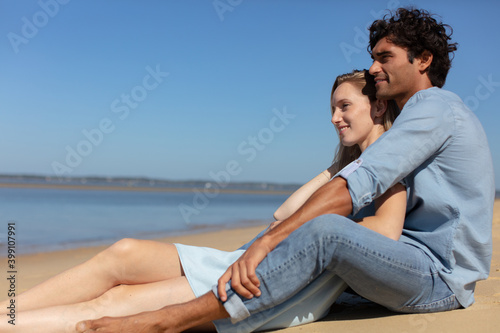 pretty young couple sitting on the beach