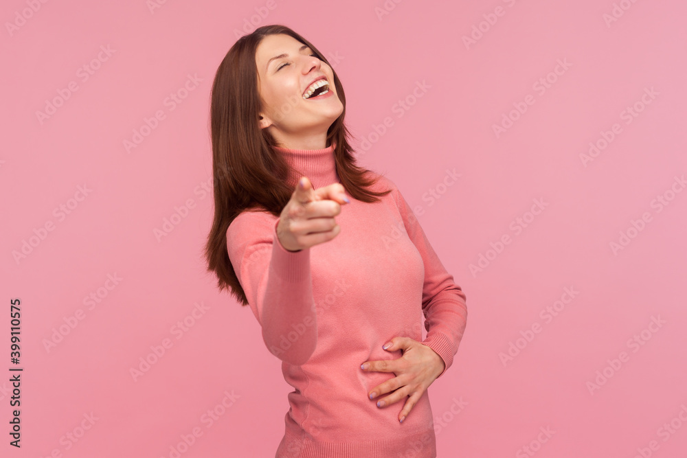 Extremely excited happy woman laughing out loud holding her belly and pointing finger at camera, wondering and mocking. Indoor studio shot isolated on pink background Extremely excited happy woman laughing out loud holding her belly and pointing finger at camera, wondering and mocking. Indoor studio shot isolated on pink background
