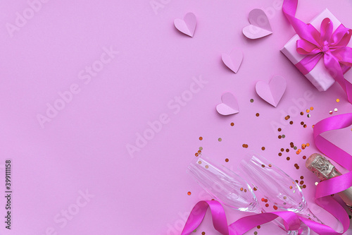 Champagne and two glasses with a gift box with a ribbon on a pink background with hearts. The concept of Valentine's Day. Flat lay, top view, copy space.