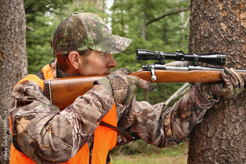 Tablou pe pânză adult hunter aiming deer rifle in forest close-up