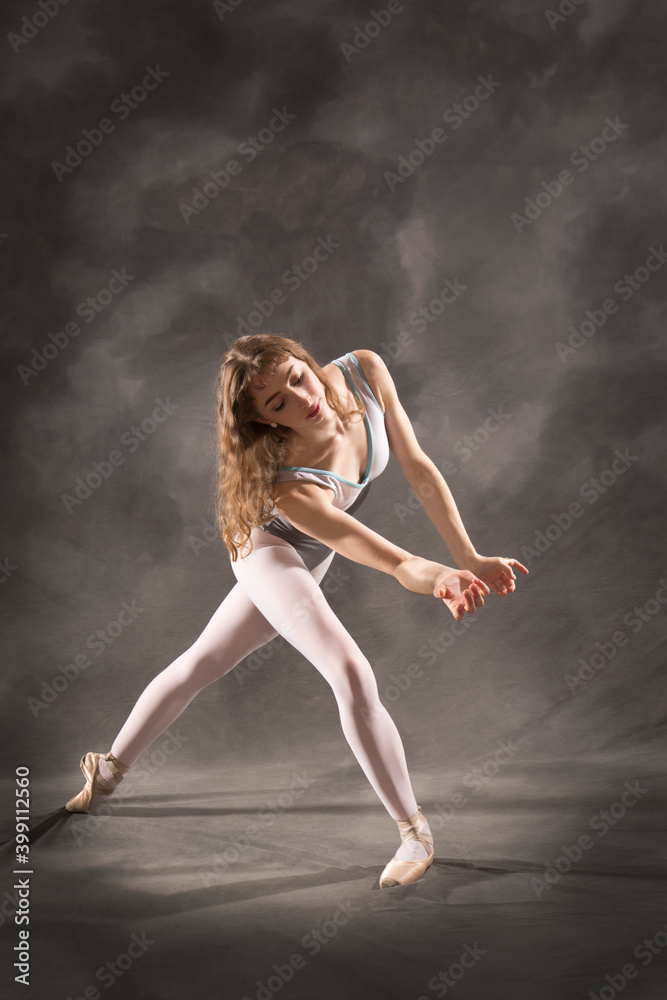 Young adult ballerina in the studio, dancing in gray leotard.