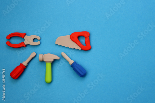 Children's mini versions of screwdrivers, saws, hammer and pliers on a blue background. Children's toolset