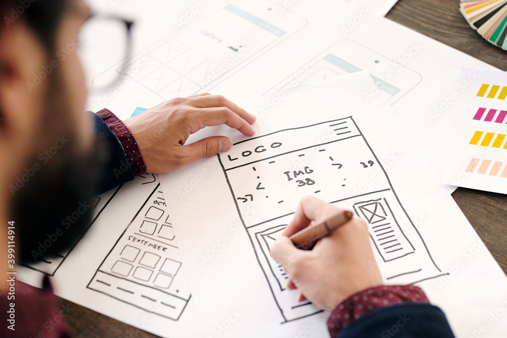 Hand of young contemporary developer of mobile application drawing sketch