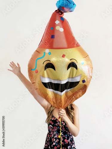 Woman holding a celebration emoji balloon in front of her face