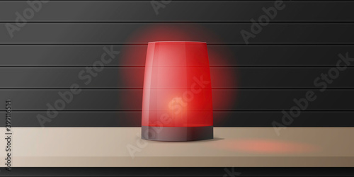 Realistic red alarm siren stands on a wooden table. Warning sign.