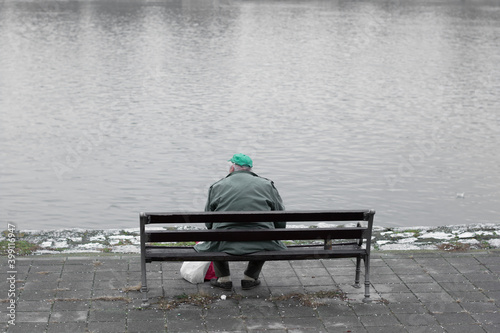 Homeless man sitting on a bench and looking at the Danube river. Emotional. 