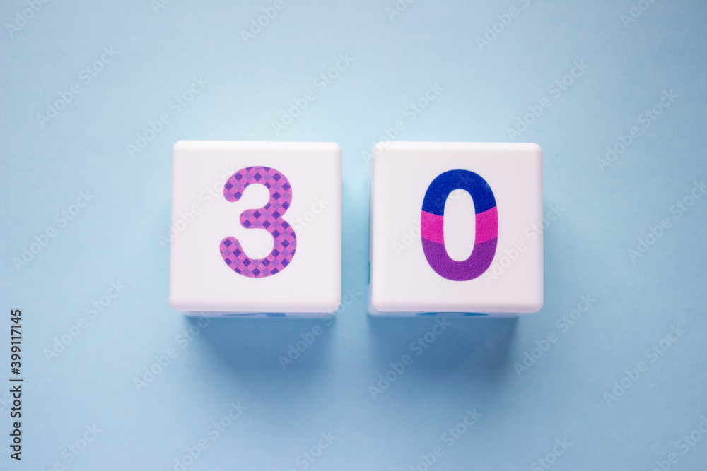 Close-up photo of a white plastic cubes with a colorful number 30 on a blue background. Object in the center of the photo Close-up photo of a white plastic cubes with a colorful number 30 on a blue background. Object in the center of the photo