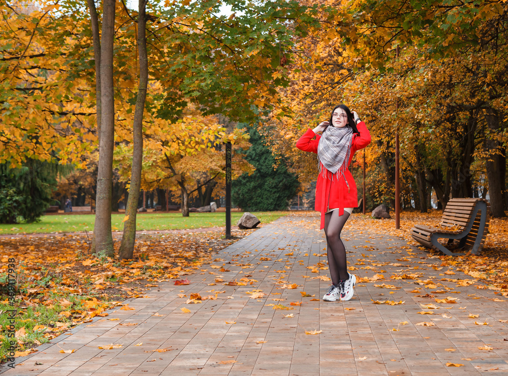 Fototapeta premium young girl in a red coat standing on the alley
