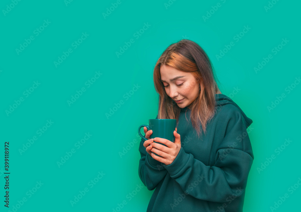 Girl with a cup in her hands on a turquoise background. Close up studio portrait. Copy, empty space for text. Girl with a cup in her hands on a turquoise background. Close up studio portrait. Copy, empty space for text.