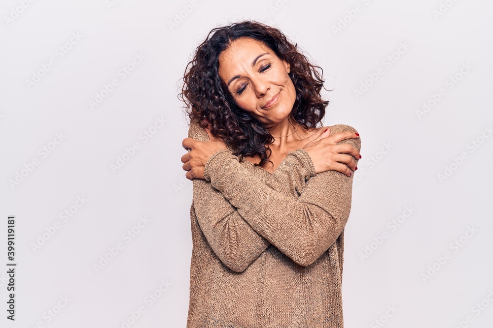 Middle age beautiful woman wearing casual sweater hugging oneself happy and positive, smiling confident. self love and self care Middle age beautiful woman wearing casual sweater hugging oneself happy and positive, smiling confident. self love and self care