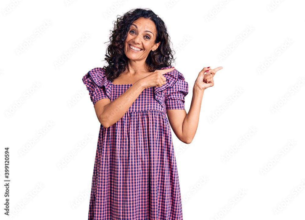 Middle age beautiful woman wearing casual dress smiling and looking at the camera pointing with two hands and fingers to the side. Middle age beautiful woman wearing casual dress smiling and looking at the camera pointing with two hands and fingers to the side.