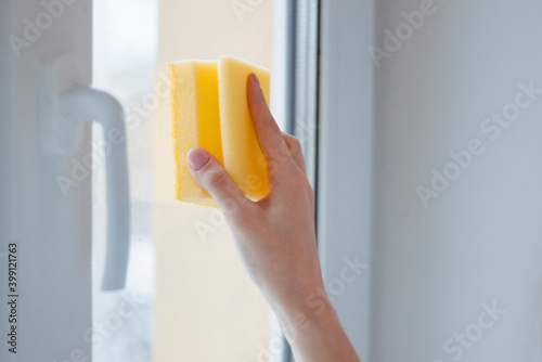 A woman s hand washes the windowsill with a yellow sponge. House cleaning