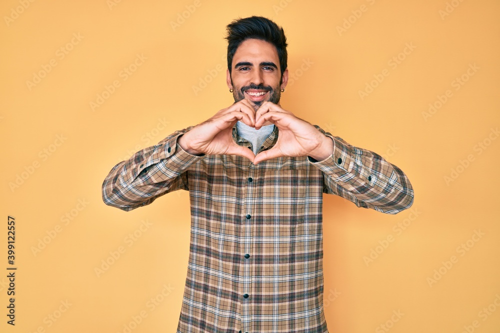 Handsome hispanic man with beard wearing casual clothes smiling in love doing heart symbol shape with hands. romantic concept. Handsome hispanic man with beard wearing casual clothes smiling in love doing heart symbol shape with hands. romantic concept.
