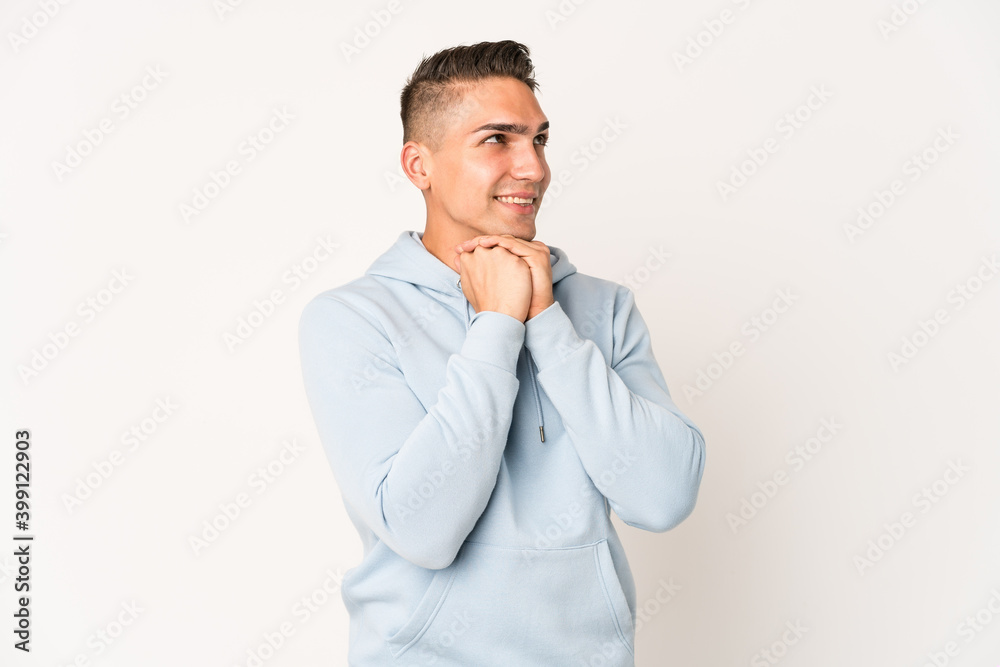 Young caucasian handsome man isolated keeps hands under chin, is looking happily aside. Young caucasian handsome man isolated keeps hands under chin, is looking happily aside.
