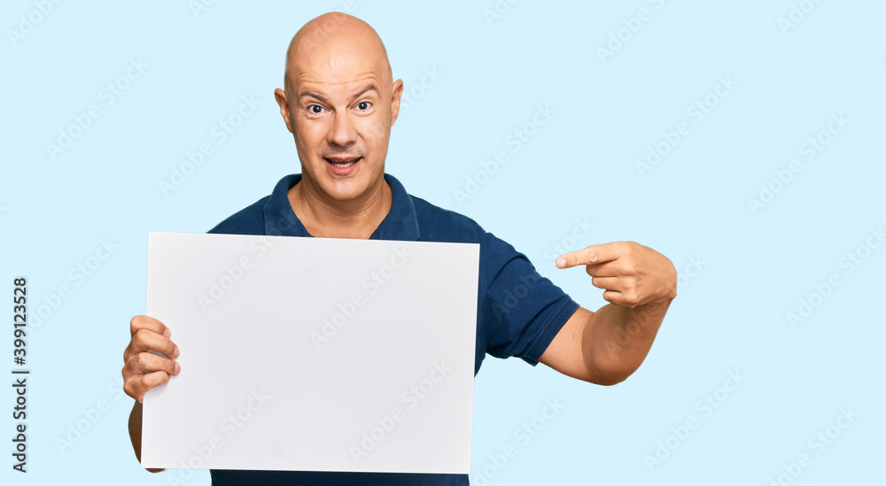 Middle age bald man holding blank empty banner smiling happy pointing with hand and finger Middle age bald man holding blank empty banner smiling happy pointing with hand and finger