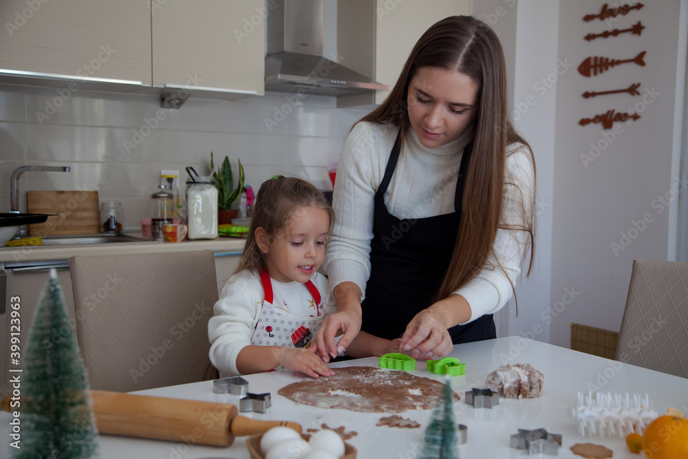 Fototapeta premium Caucasian mother and daughter cooking ginger bread in the kitchen. Christmas cooking concept. Mother and daughter cooking concept.