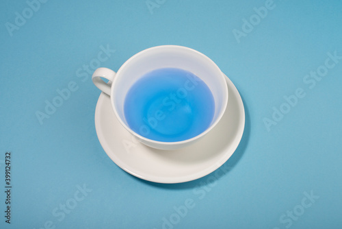 White cup with blue liquid on blue background. Blue Monday. Happy Monday.