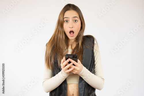 Image of joyful caucasian woman holding cellphone in shock isolated over white background