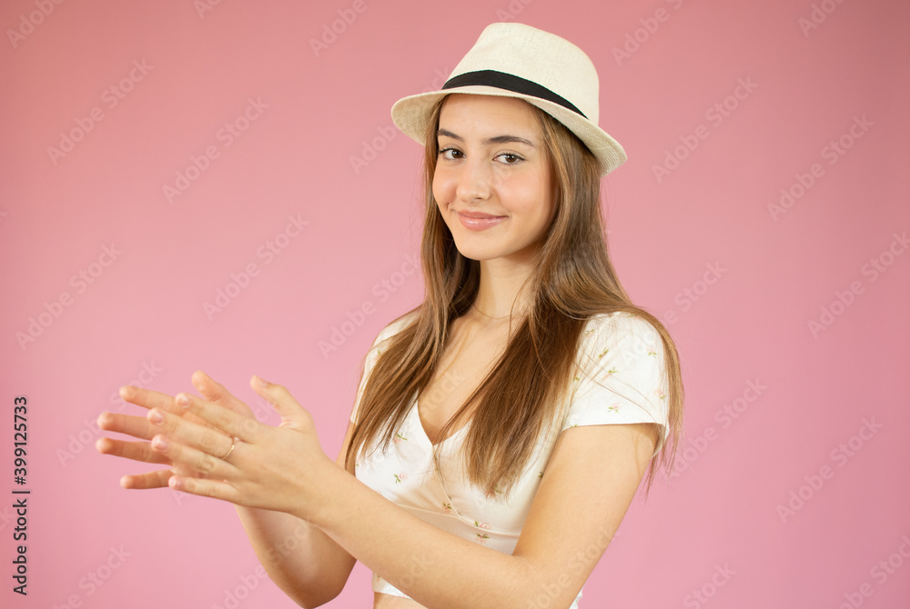 Young pretty girl feeling happy and successful, smiling and clapping hands, saying congratulations with an applause against pink wall Young pretty girl feeling happy and successful, smiling and clapping hands, saying congratulations with an applause against pink wall