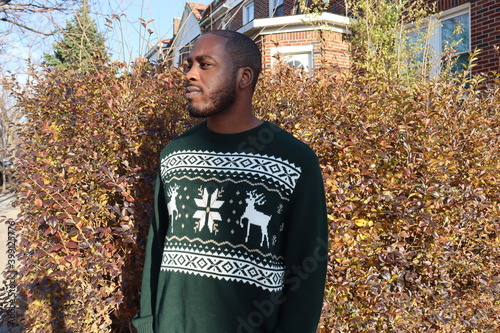 Black man wearing green Christmas sweater standing outdoors  photo