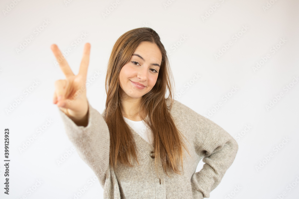 Portrait of cheerful young woman showing two fingers or victory gesture, over white background Portrait of cheerful young woman showing two fingers or victory gesture, over white background
