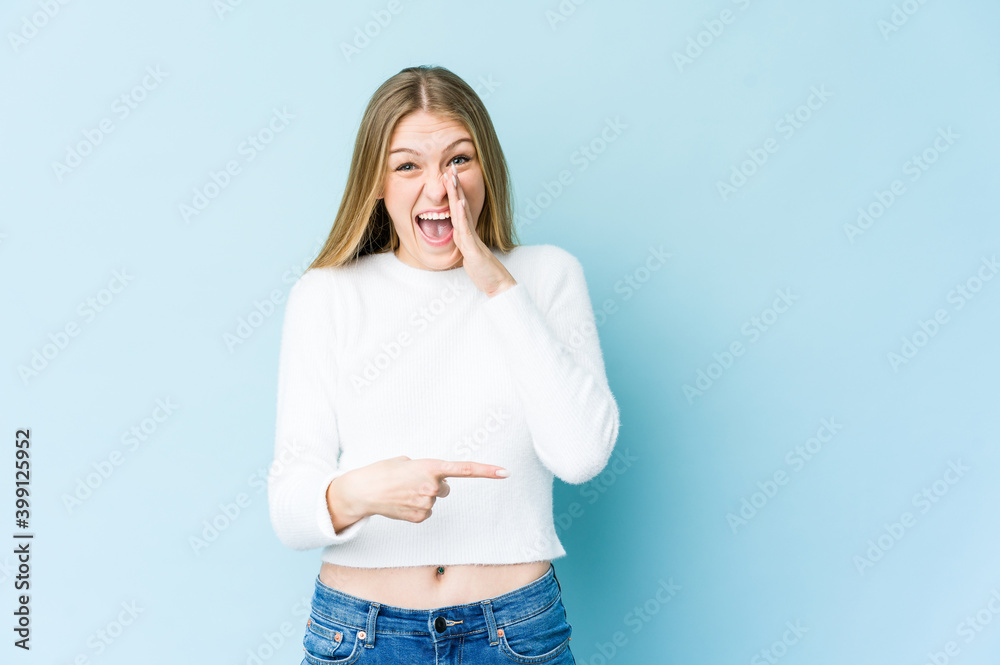Young blonde woman isolated on blue background saying a gossip, pointing to side reporting something. Young blonde woman isolated on blue background saying a gossip, pointing to side reporting something.