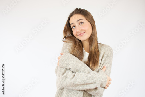 Young beautiful woman wearing sweater over white isolated background Hugging oneself happy and positive, smiling confident. Self love and self care © Danko