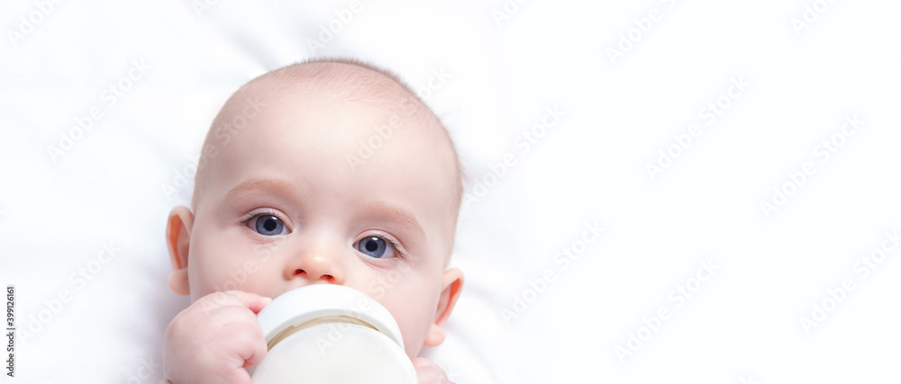 Banner with baby milk bottle in hands. Copy space. Infant drinking milk. First bottle for baby. Artificial feed concept. Top view. Cute caucasian boy. Banner with baby milk bottle in hands. Copy space. Infant drinking milk. First bottle for baby. Artificial feed concept. Top view. Cute caucasian boy.