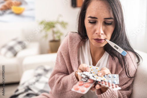 Desperate flu-having female holds various medication packagings not knowing which one to choose