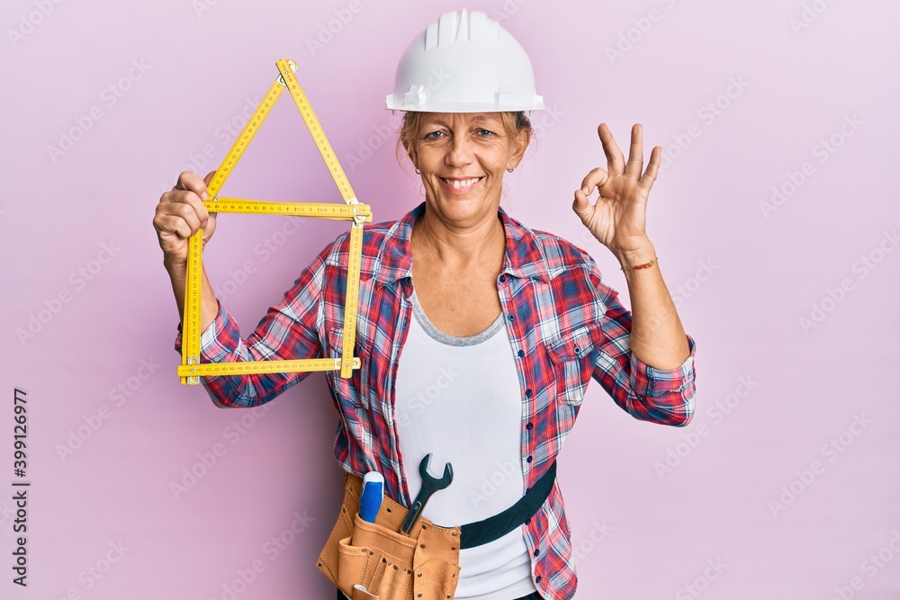 Middle age blonde woman wearing architect hardhat holding build project doing ok sign with fingers, smiling friendly gesturing excellent symbol Middle age blonde woman wearing architect hardhat holding build project doing ok sign with fingers, smiling friendly gesturing excellent symbol
