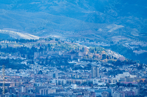 Unusual distant view of the Alhambra with the city of Granada at its feet and the mountains in the background