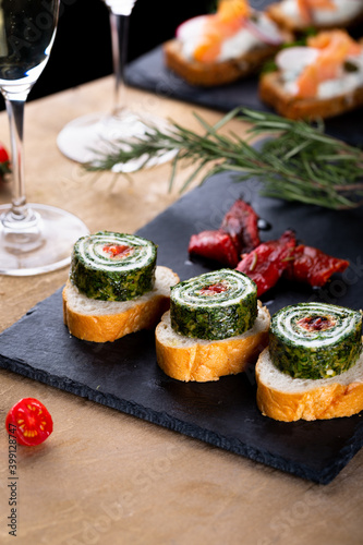Christmas tapas with spinach rolls and dried tomatoes. New year celebration with white wine, toasts for party dinner