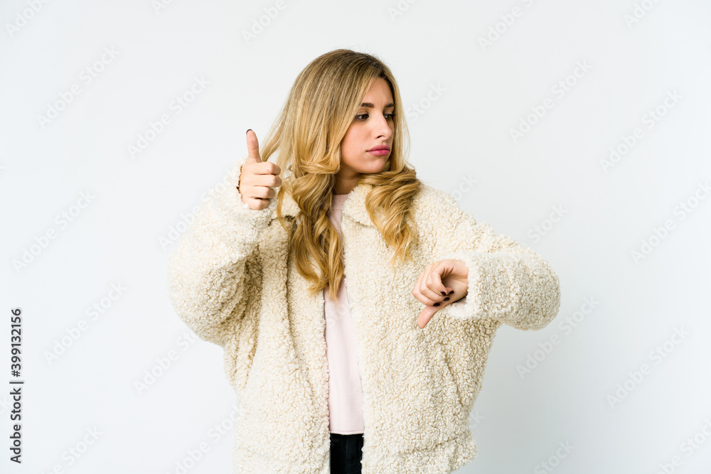 Young caucasian blonde woman showing thumbs up and thumbs down, difficult choose concept Young caucasian blonde woman showing thumbs up and thumbs down, difficult choose concept